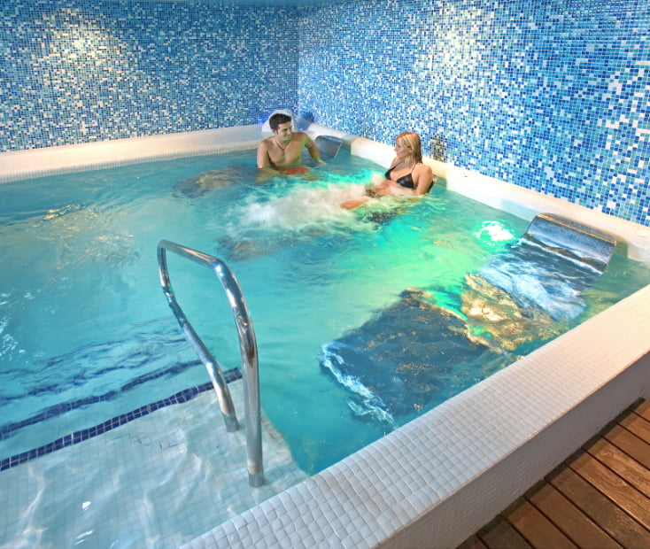 Couple lying in hammocks submerged in the whirlpool pool