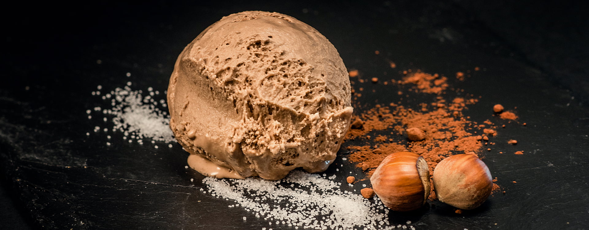 Plato de postre con una bola de helado acompañada con avellanas