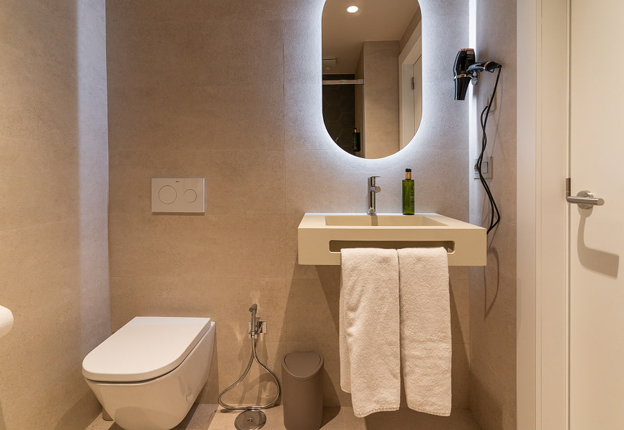 Baño con lavabo, espejo retroiluminado, toallas, amenities y secador de pelo
