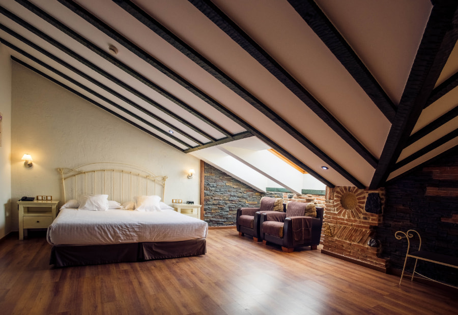 Attic room with double bed and two armchairs